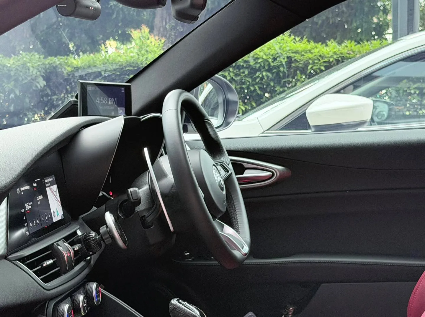 Interior view of a car showing steering wheel, dashboard, and windscreen with tinted windows.