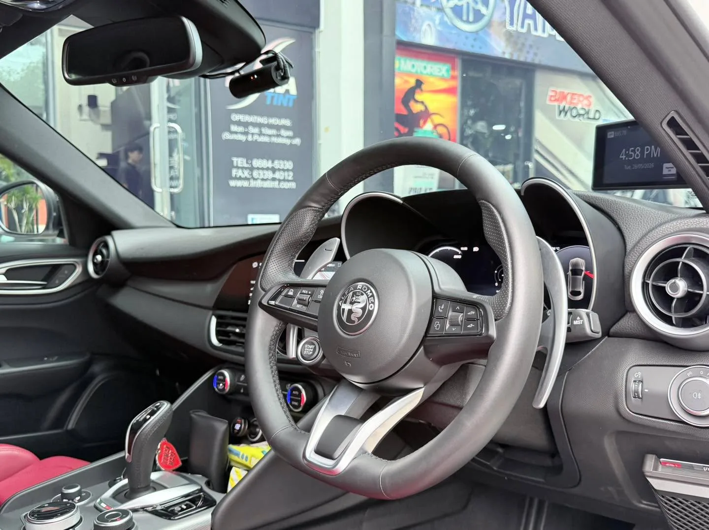Close-up of steering wheel and dashboard interior with leather trim and control buttons visible.