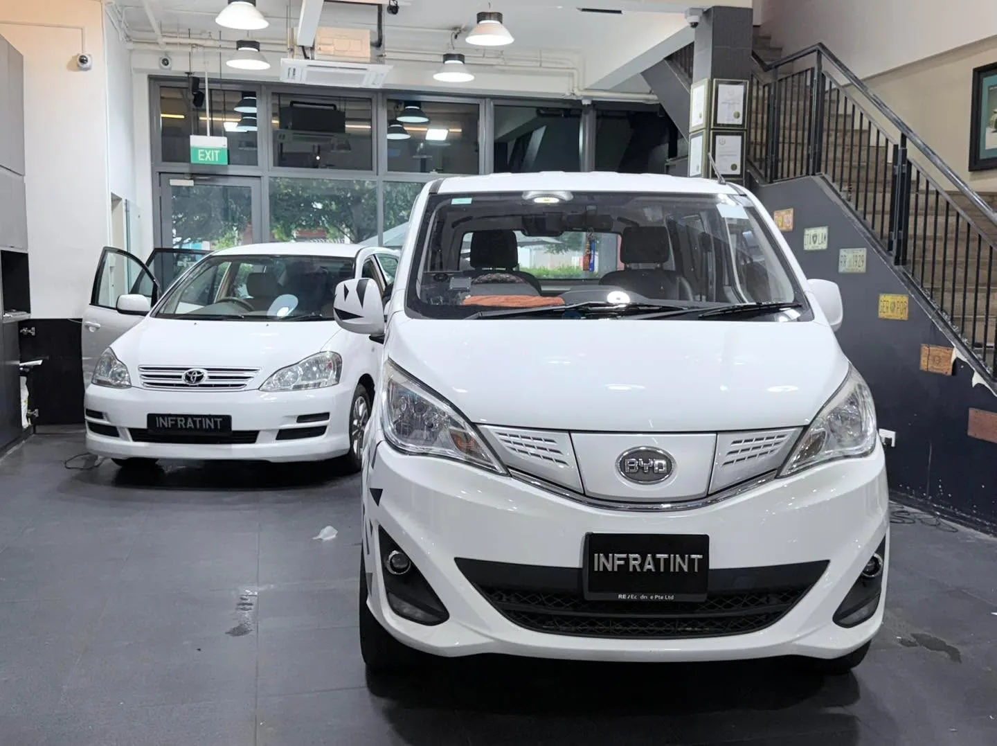 A white BYD T3 hatchback and white Toyota Picnic in the workshop.