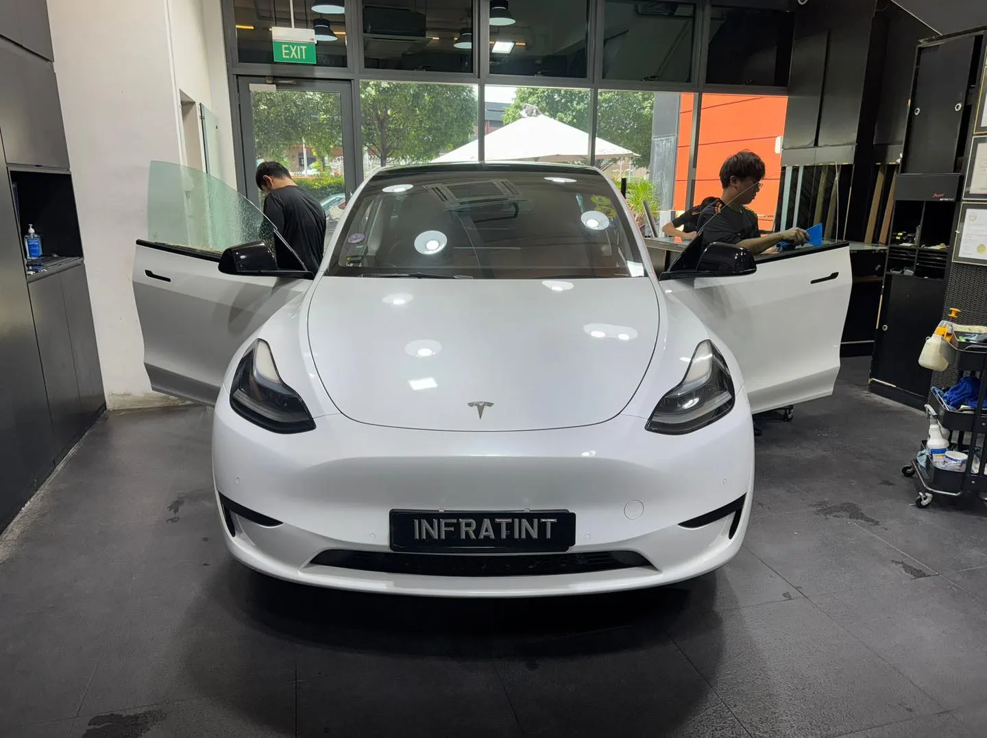 A white Hyundai i30 hatchback with doors open, two technicians working inside.