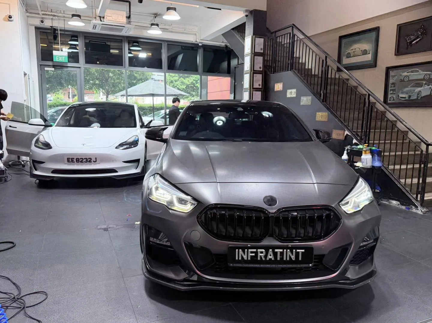 A white Mercedes-Benz sedan with doors open and a white Tesla vehicle visible alongside.
