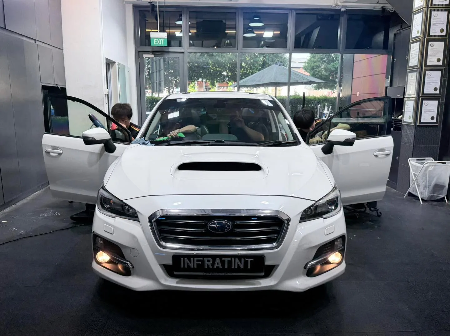 A white Subaru wagon with open doors during tinting work at Infratint.