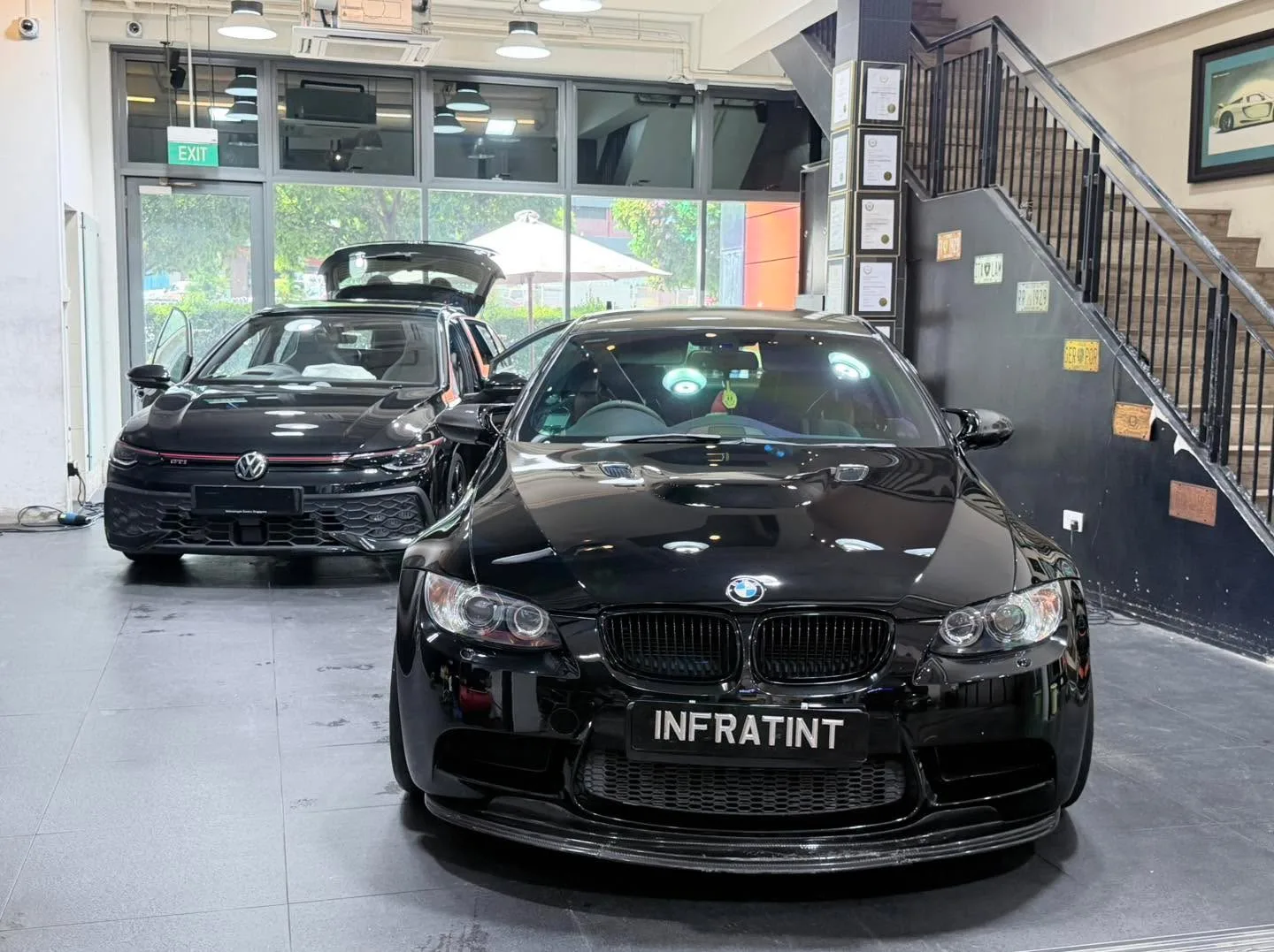 A black BMW M3 saloon and a black Volkswagen GTI hatchback in the workshop.