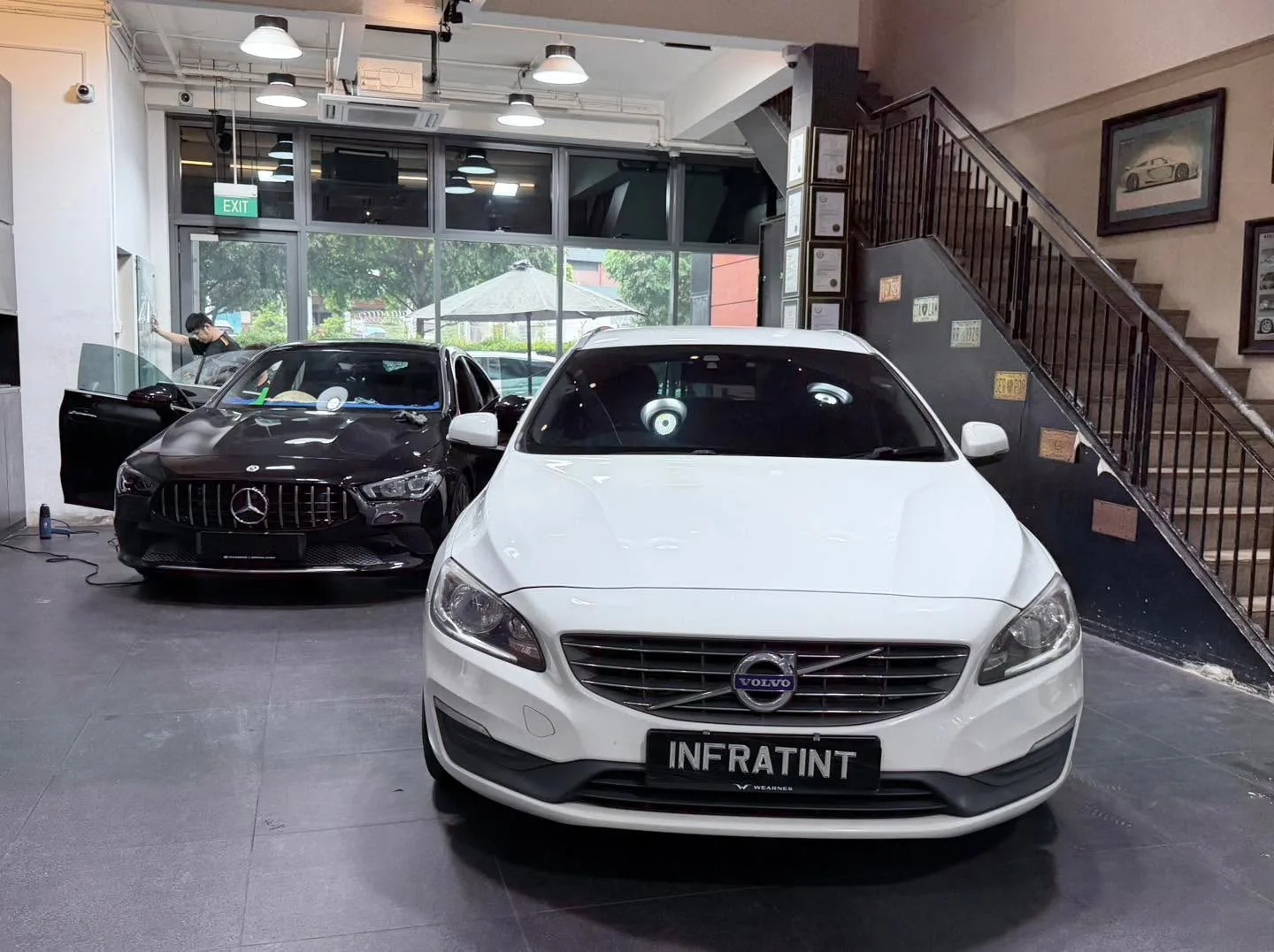 A white Volvo V60 saloon parked indoors with a black Mercedes-Benz sedan visible to the left.