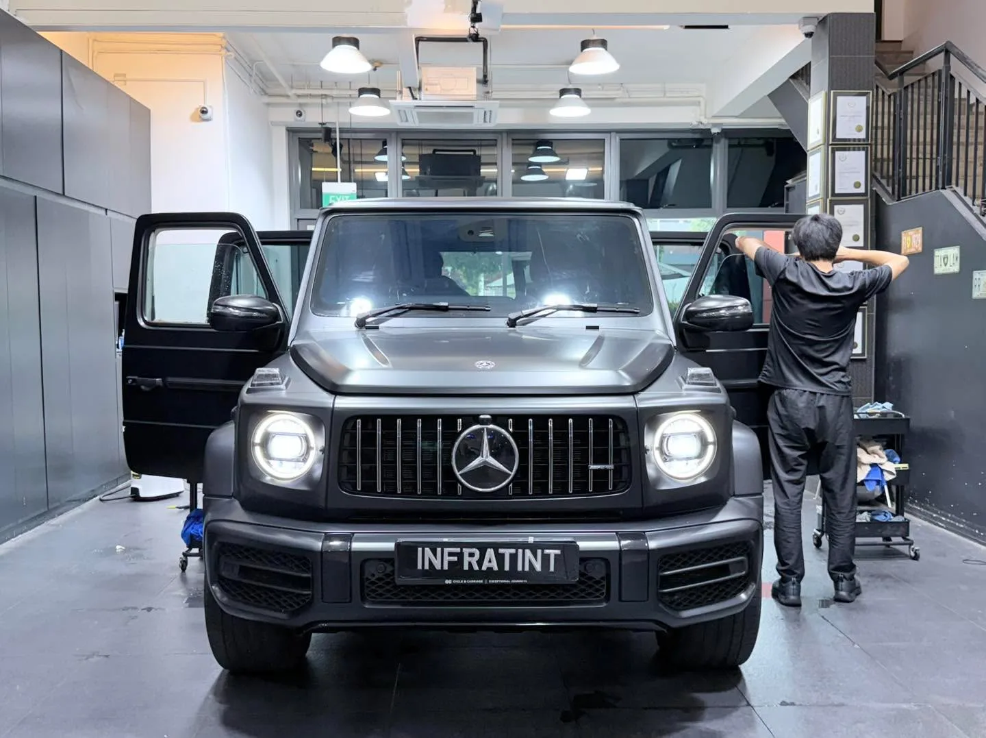 A black Mercedes-Benz G-Class SUV with doors open, being prepared for window tinting.