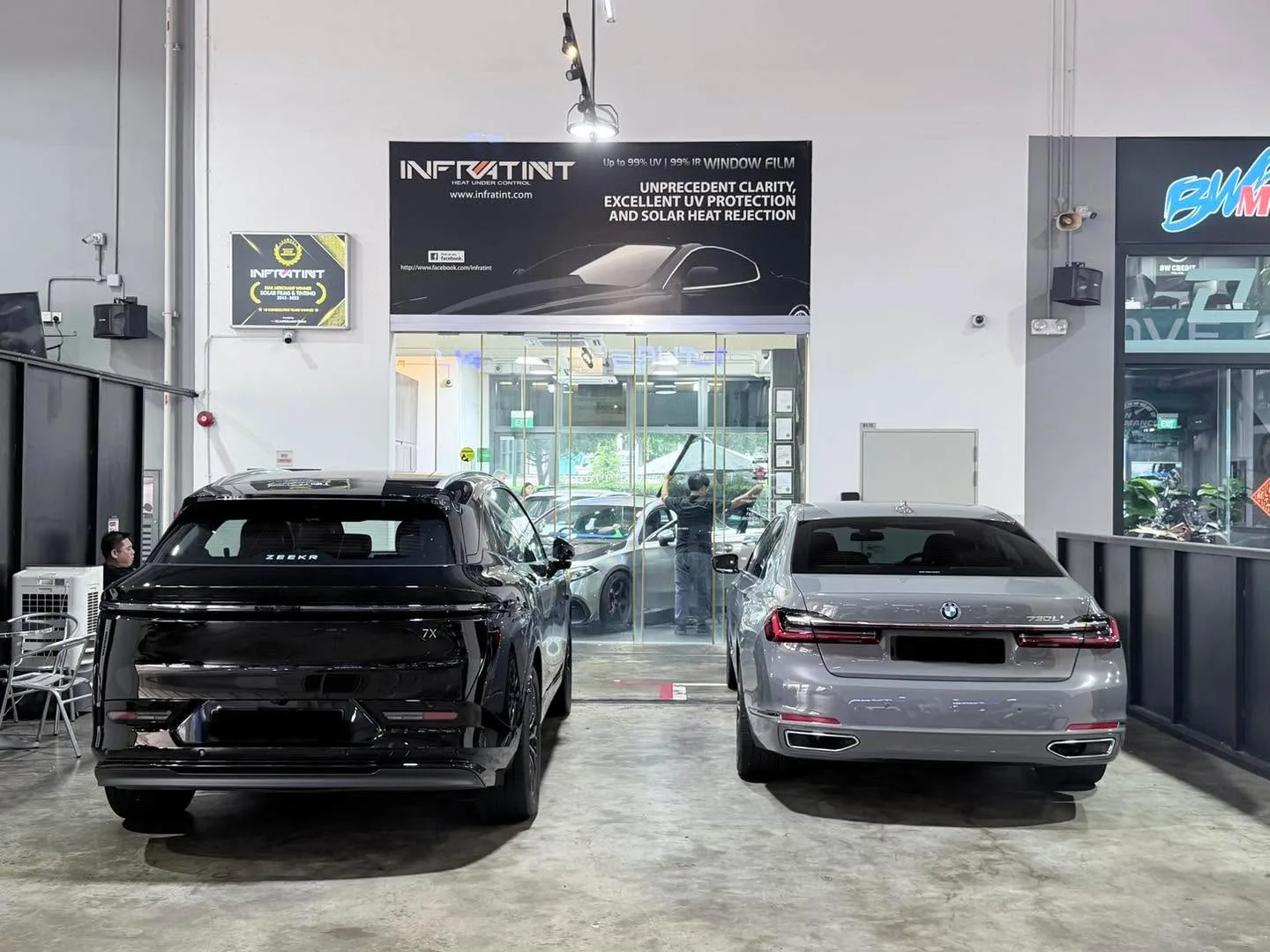 A black SUV and a silver sedan parked in the workshop garage with Infratint signage visible.