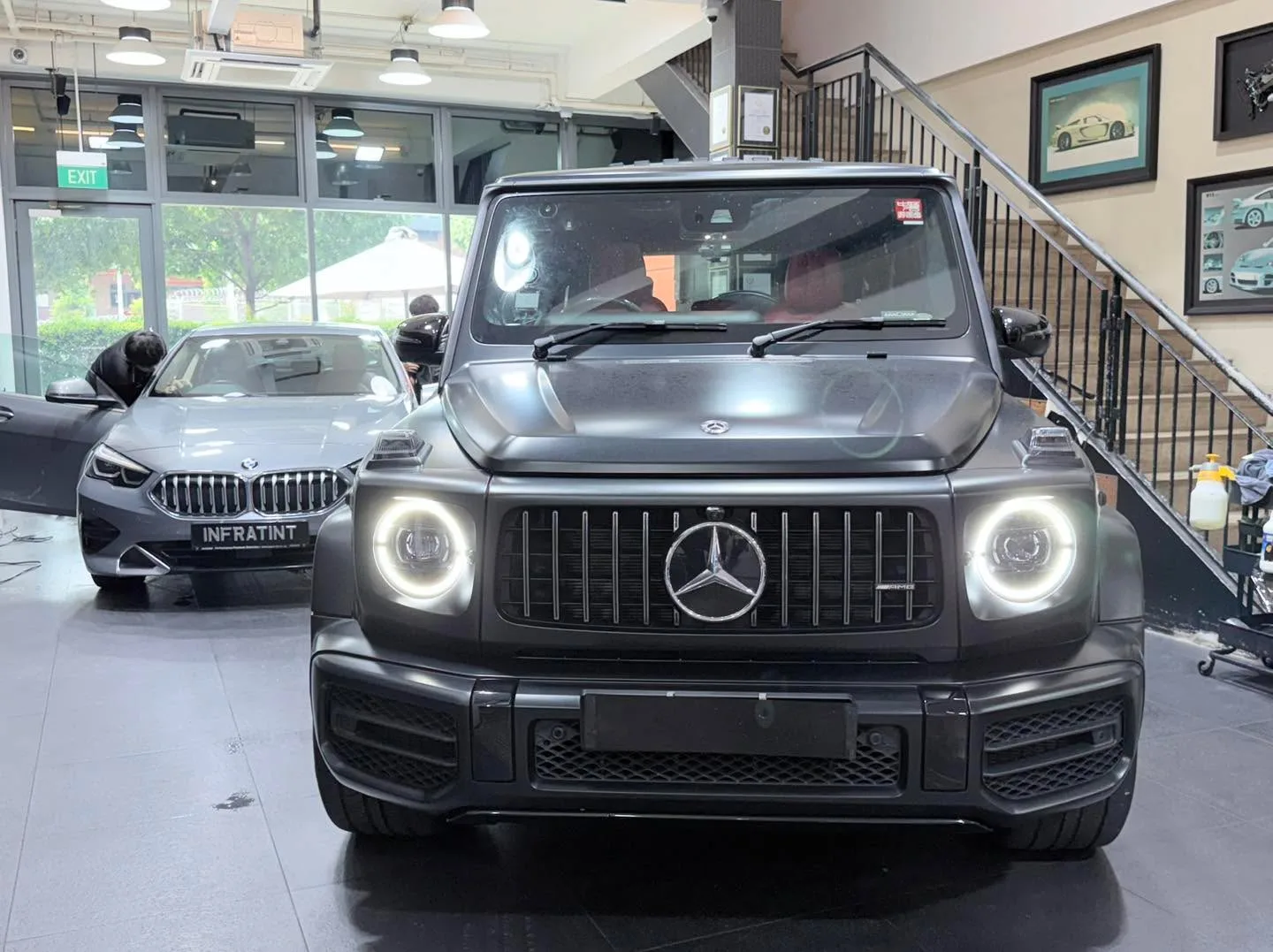 A black Mercedes-Benz G-Class SUV with round headlights facing forward in the workshop.