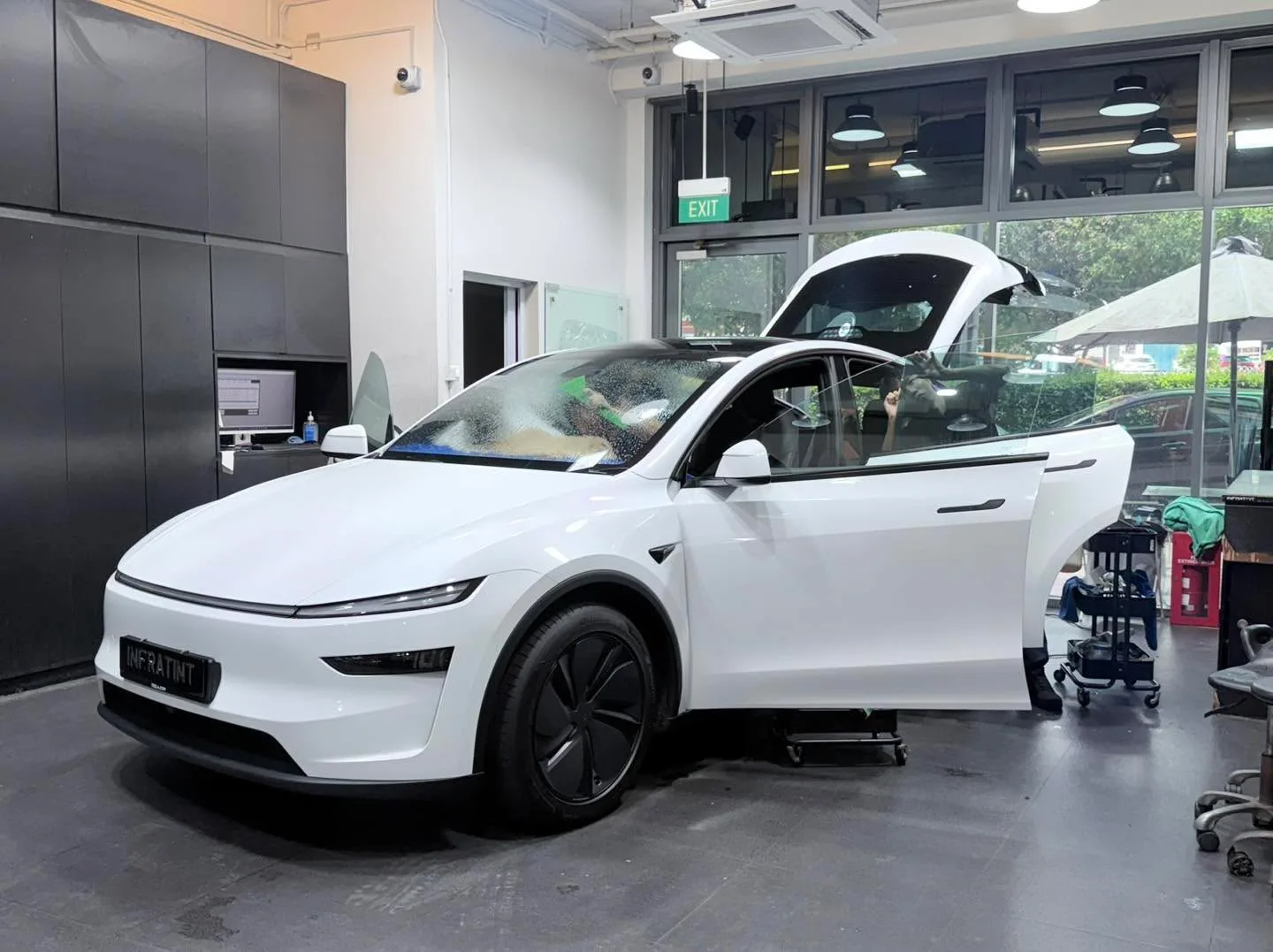 A white Tesla Model Y electric car with open doors being worked on.