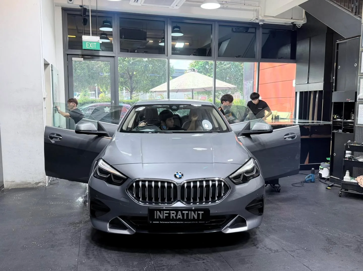 A white BMW 2 Series hatchback with open doors in the workshop.