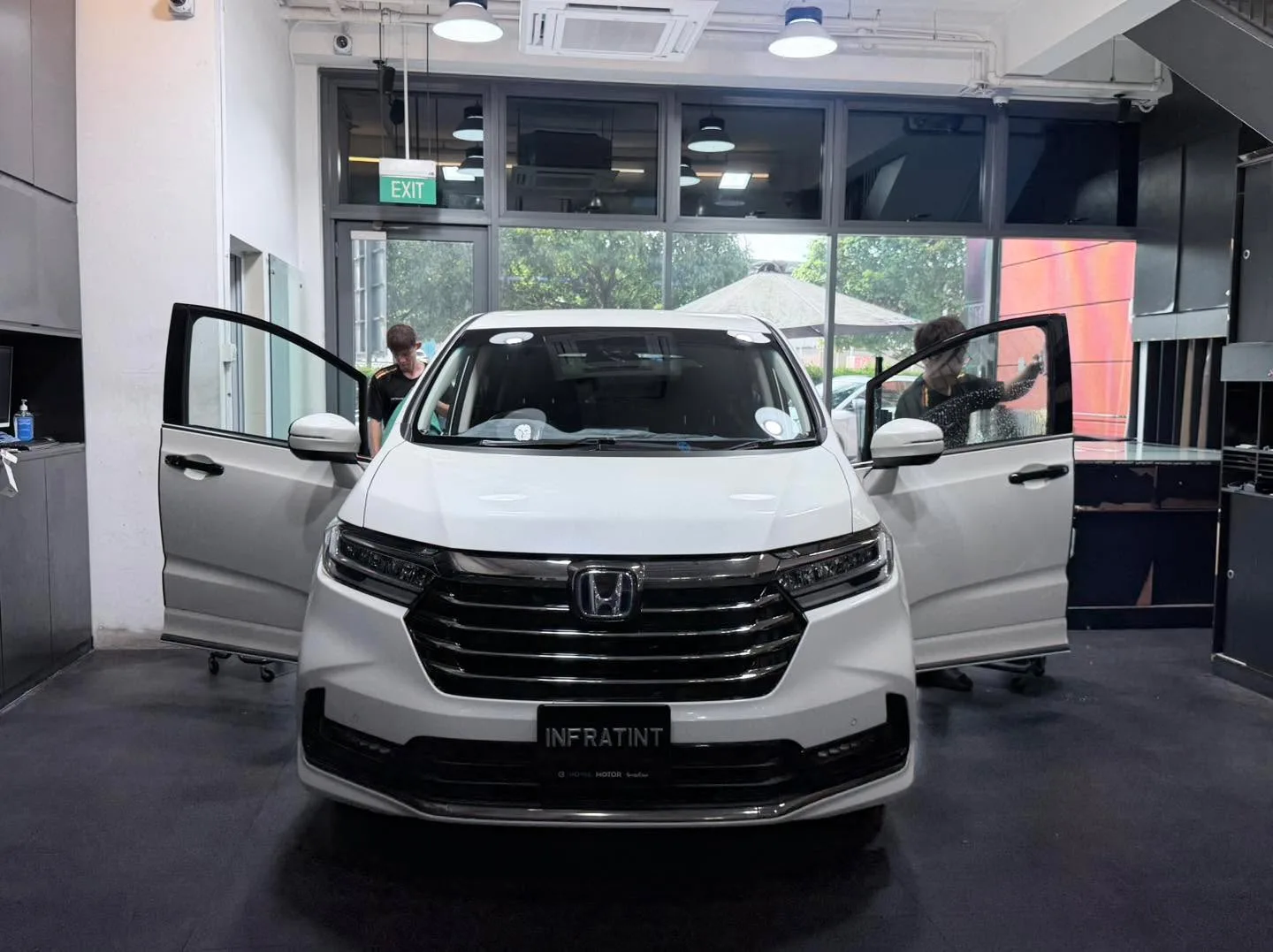 A white Honda Odyssey with open doors being tinted at Infratint.