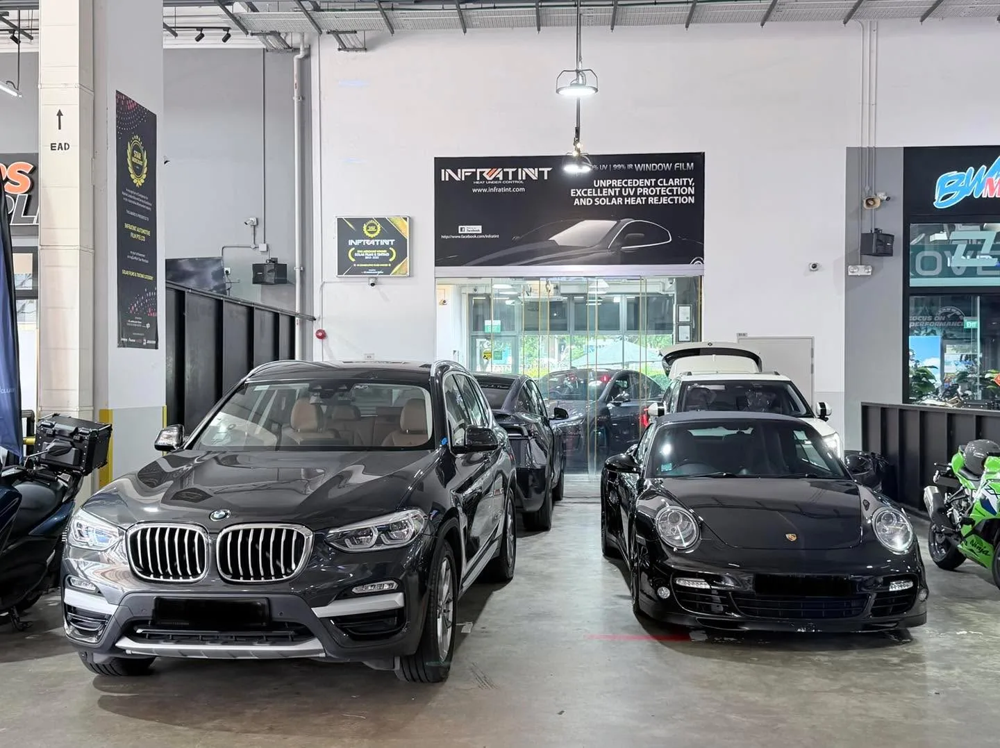 A black BMW and a dark Porsche sports car indoors.