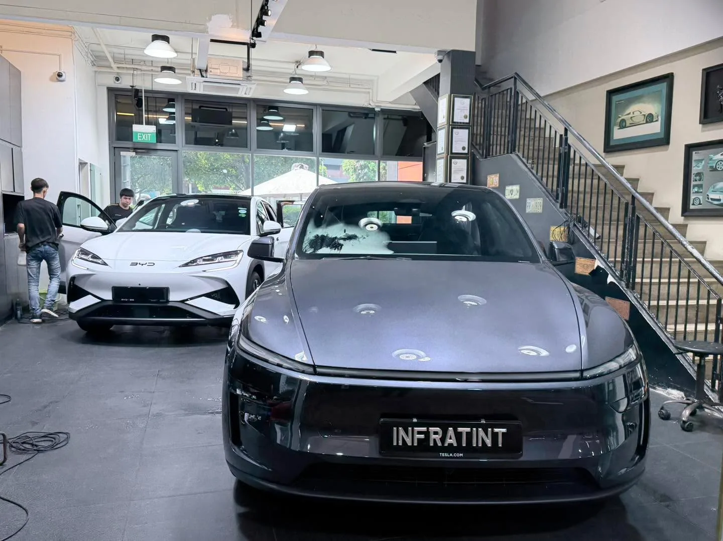 A white BMW and black Tesla saloon with open doors.
