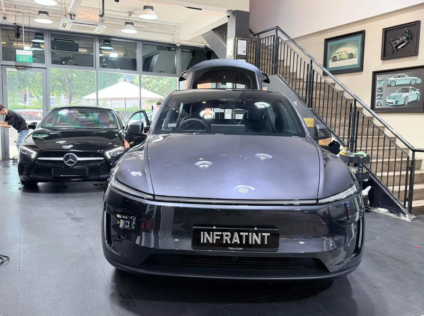 A grey Tesla and a grey Mercedes SUV parked together.
