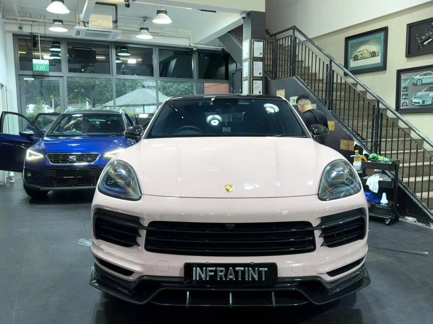 A white Porsche Cayenne facing forward at the workshop interior.