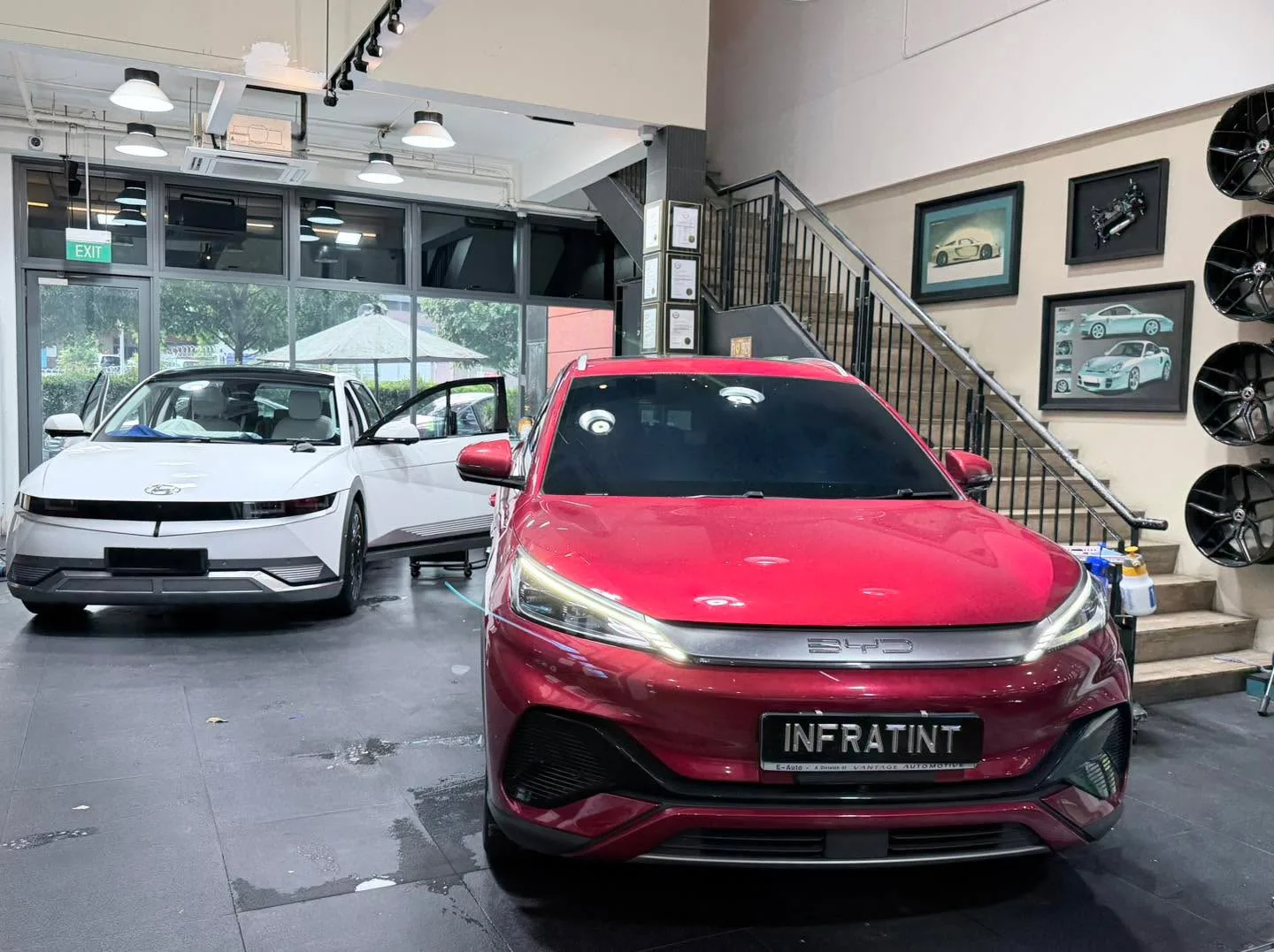 A white Hyundai Ioniq 5 and a red BYD Atto 3 at the workshop.