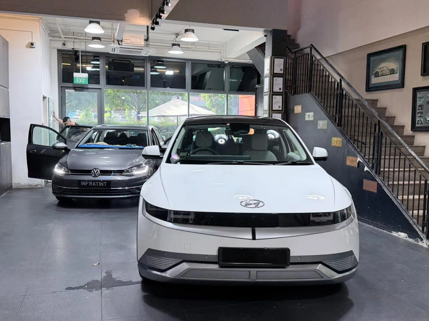 A white Volkswagen Golf hatchback and a red BYD Atto 3 at the workshop.
