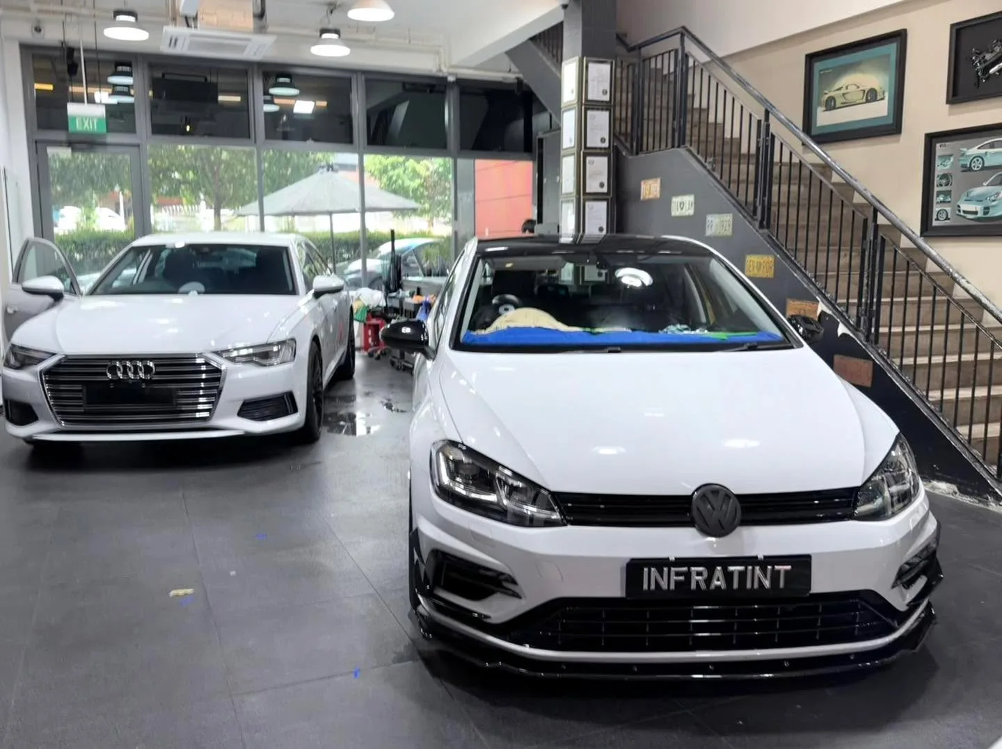 A white Audi A6 sedan and a white Volkswagen Golf hatchback at the workshop.