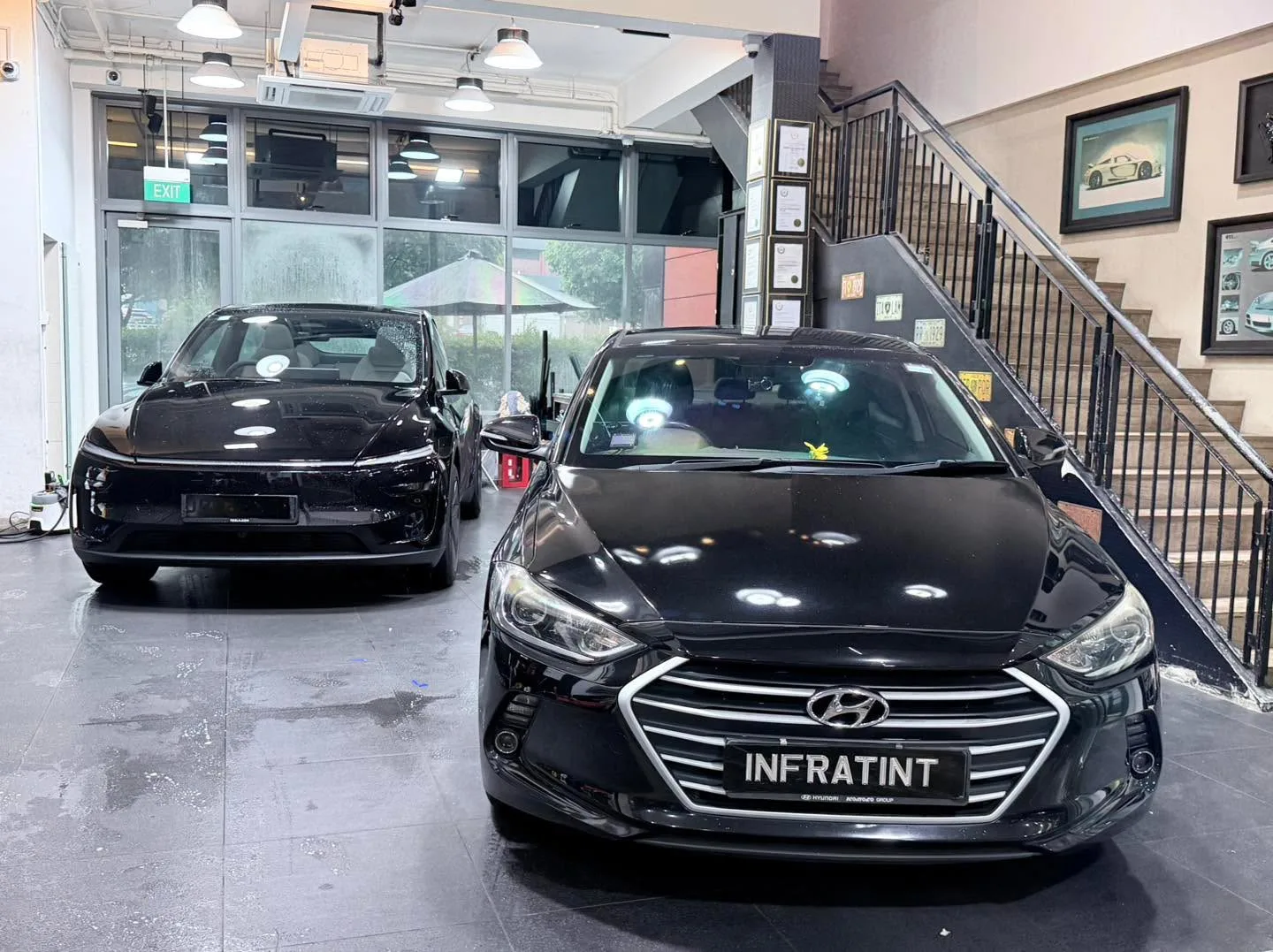 Two black sedans in the workshop, one with distinctive quad headlights.