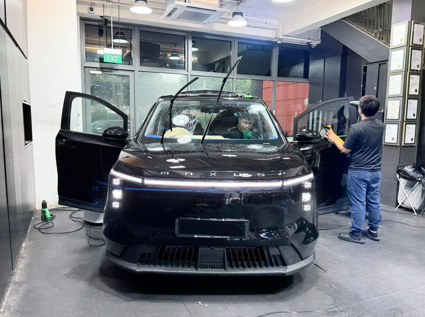 A black electric SUV with open door undergoing window tinting application.