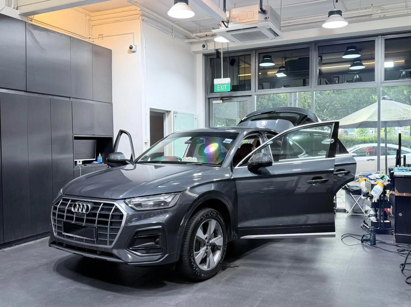 A dark grey Audi Q5 SUV with doors open, parked indoors for tinting.