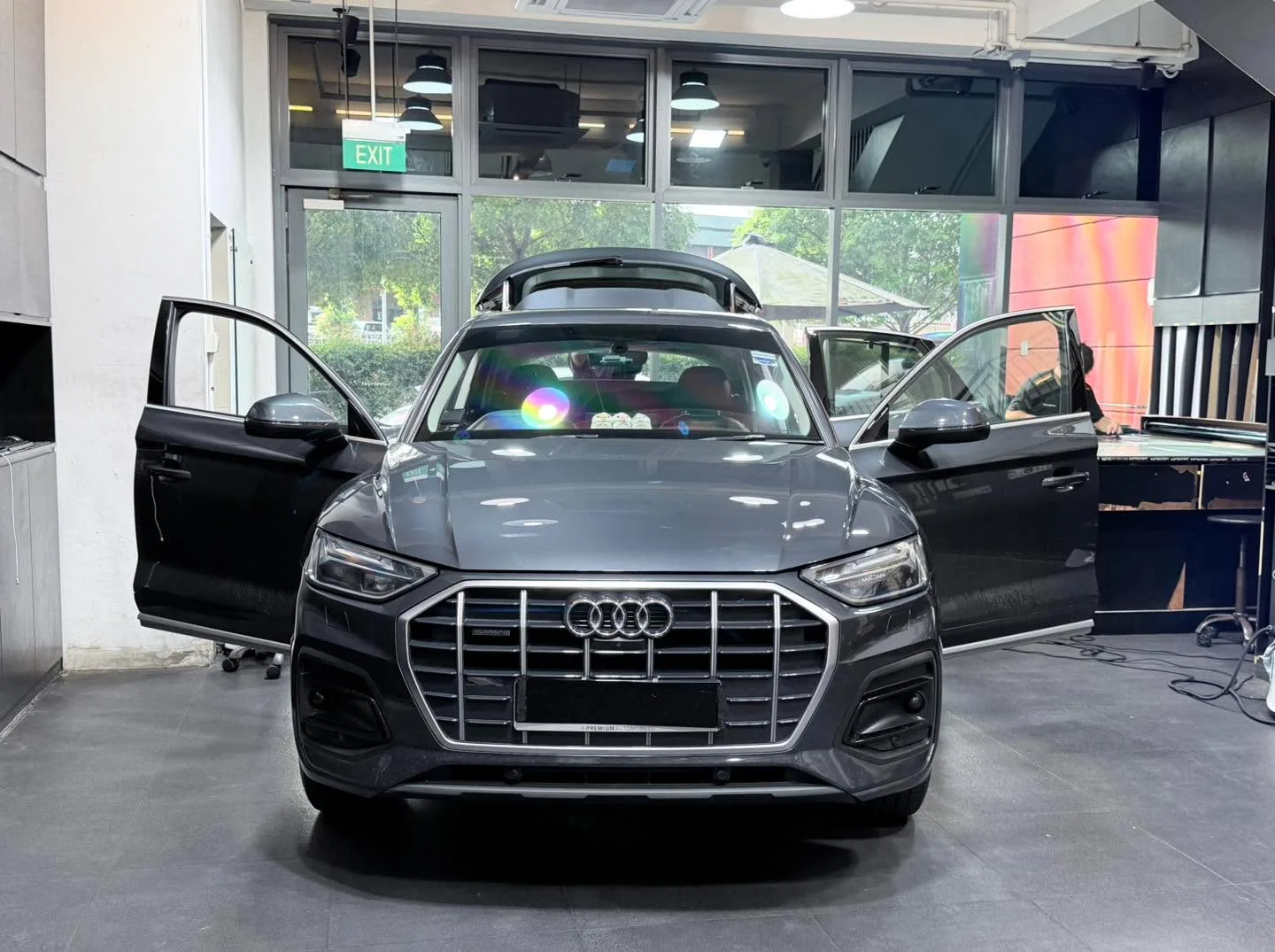 A dark grey Audi Q5 crossover with both doors open in the workshop.