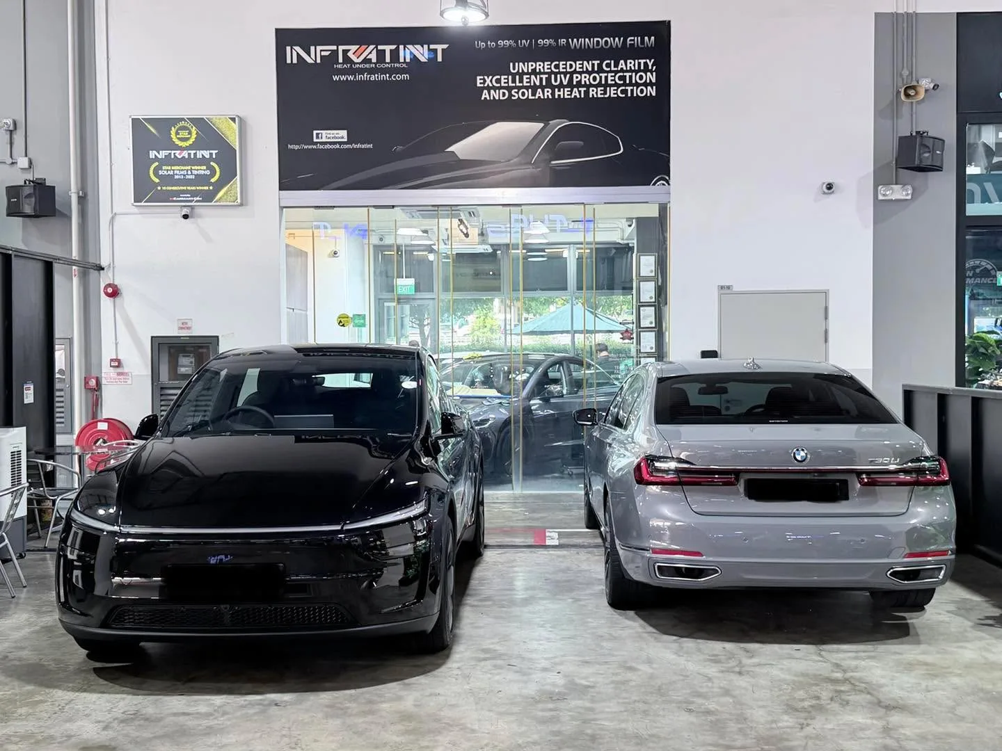 A black Tesla and a silver BMW saloon parked in the Infratint workshop.