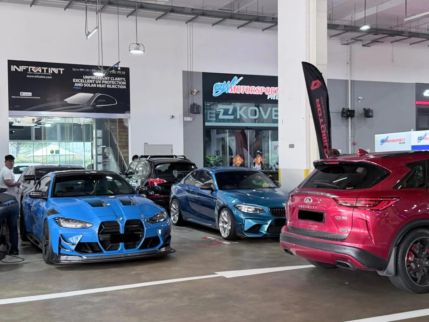 A blue BMW M440i and other cars parked at the Infratint workshop.