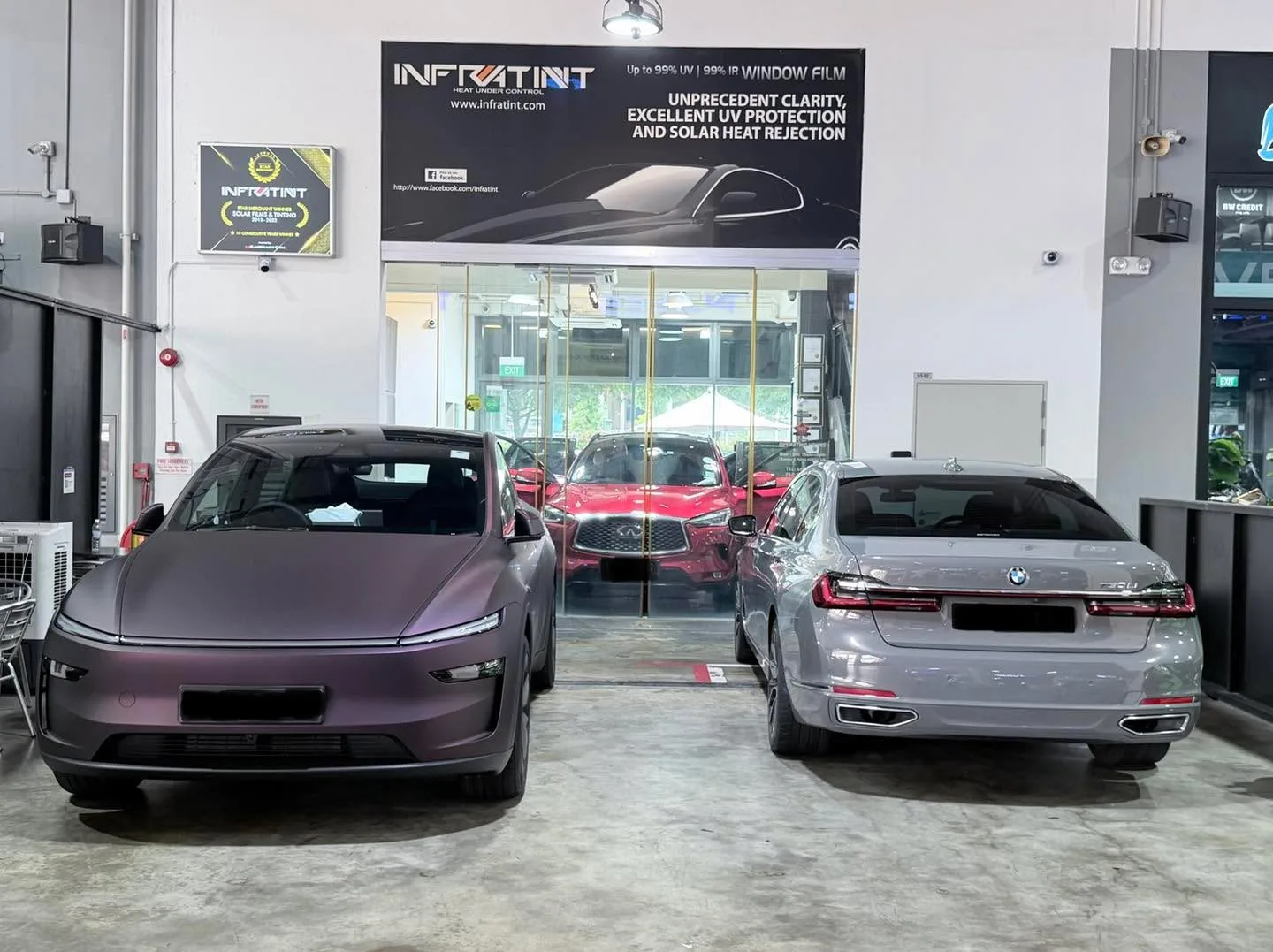 A purple Tesla and a silver BMW sedan inside the workshop.