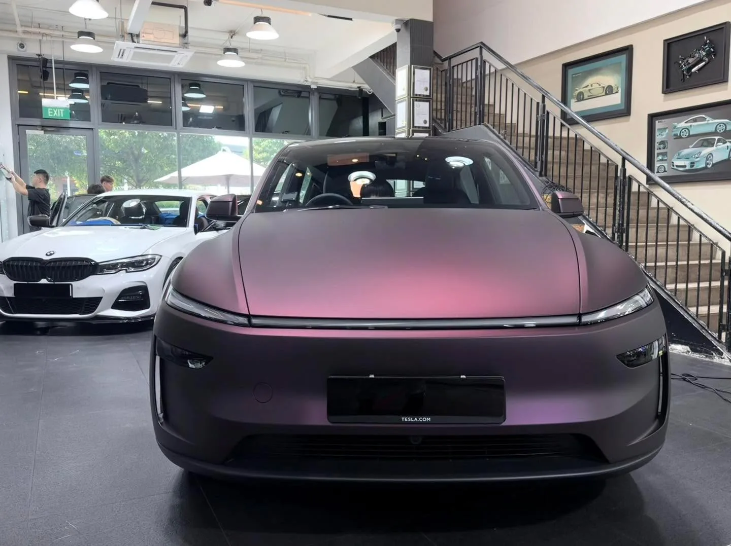 Front view of a purple Tesla with black accents inside the workshop.