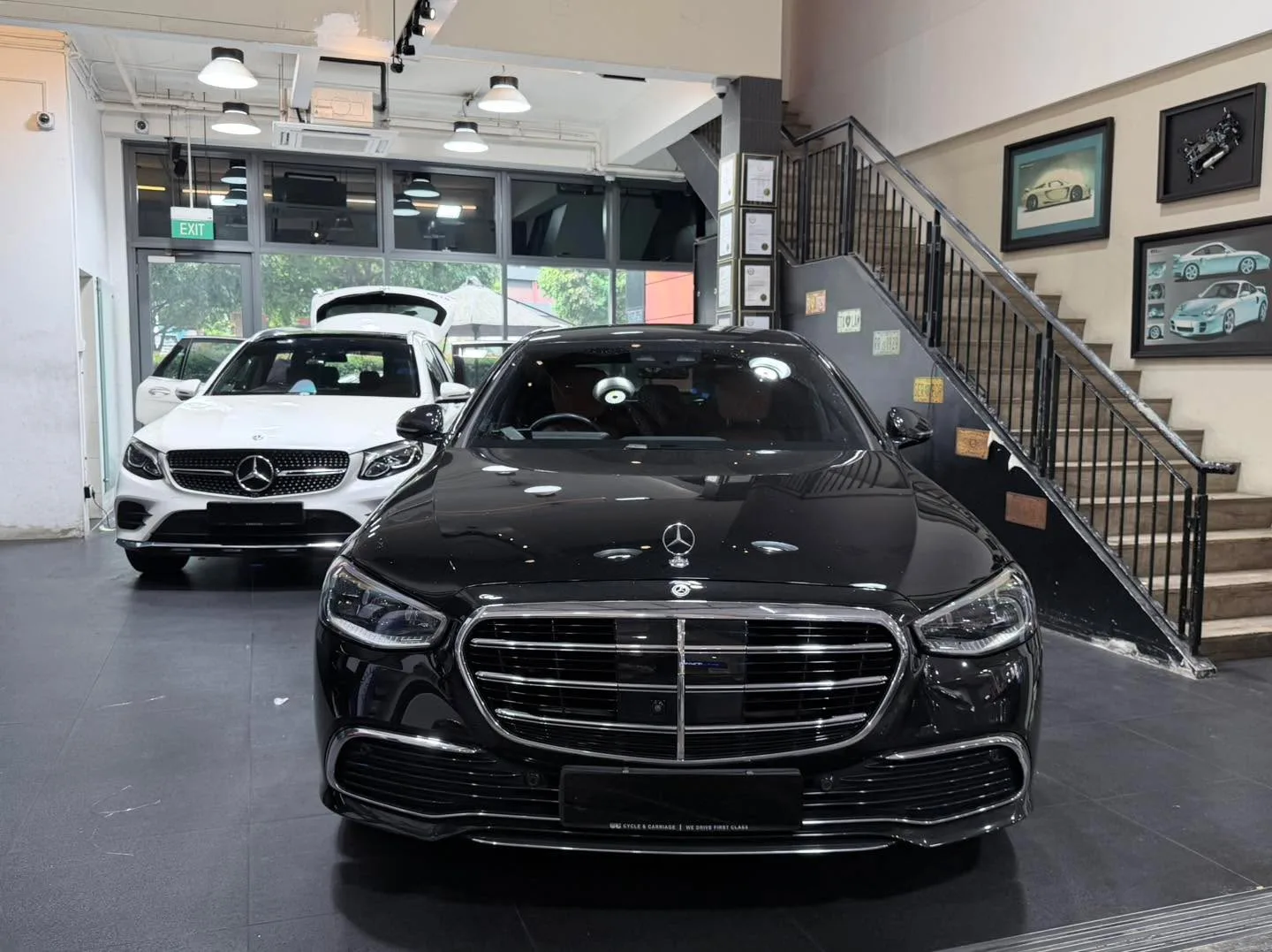 A black Mercedes-Benz sedan and a white Mercedes-Benz sedan in the workshop.