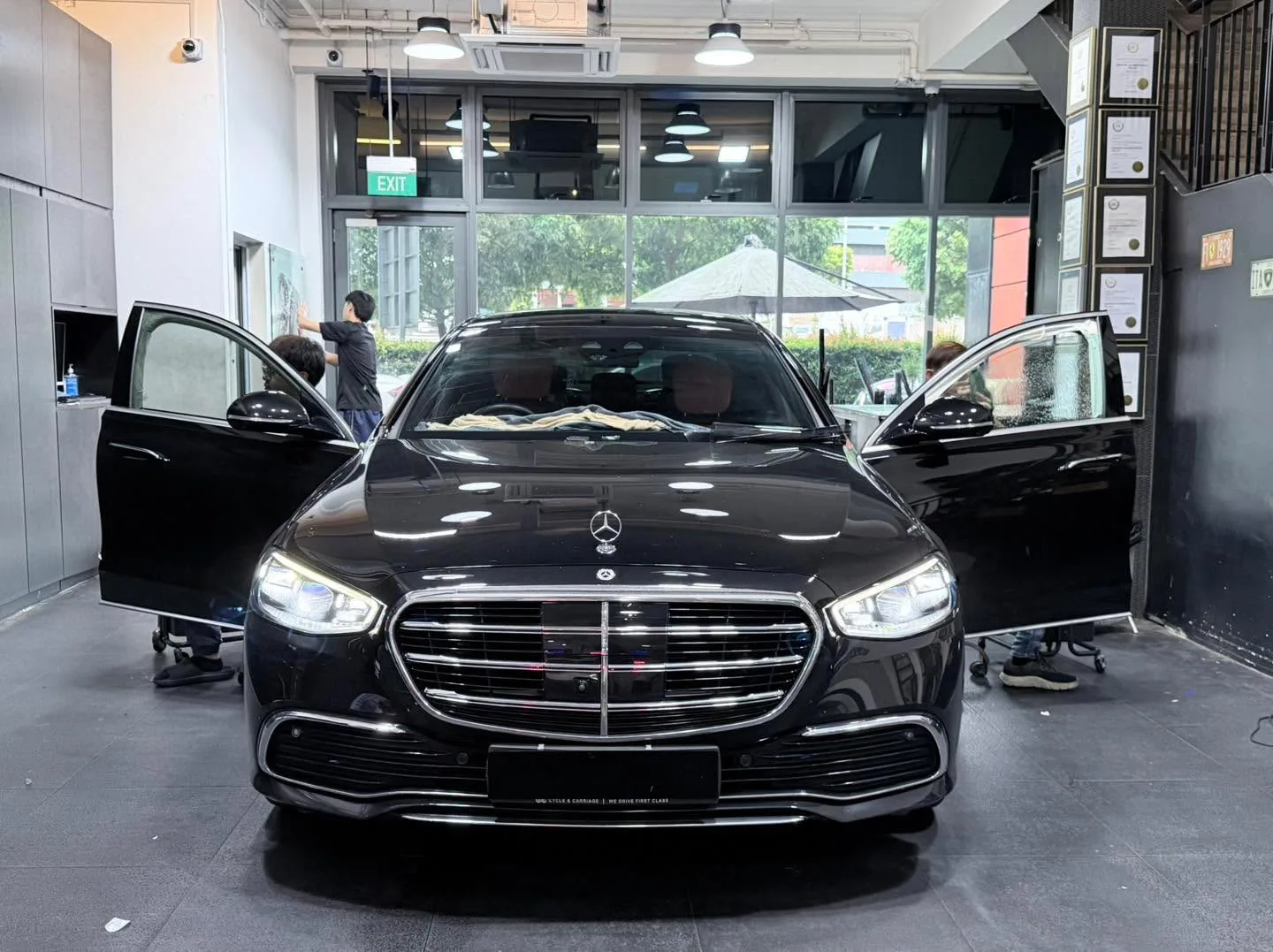 A white BMW saloon with doors open for window tinting inside the workshop.