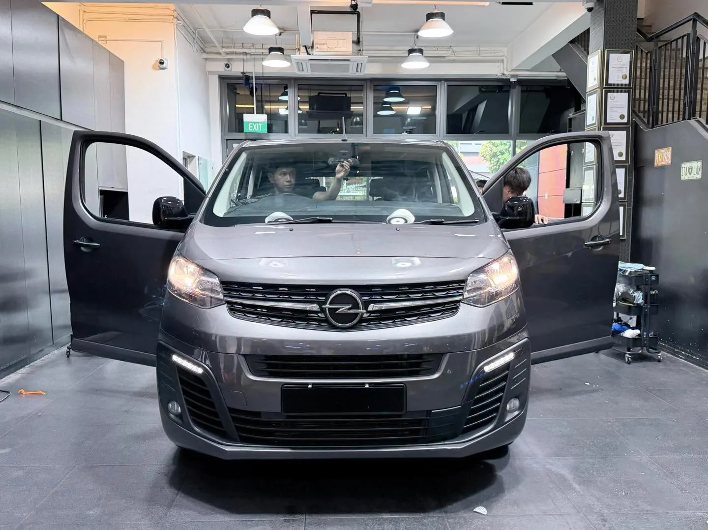 A grey Opel Zafira multi-purpose vehicle with both doors open inside the workshop.