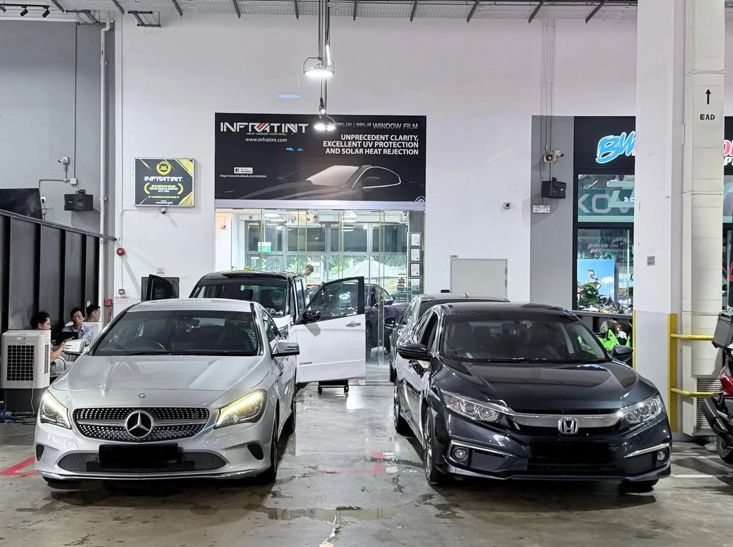 A white Mercedes-Benz compact SUV and a black Honda sedan parked indoors.