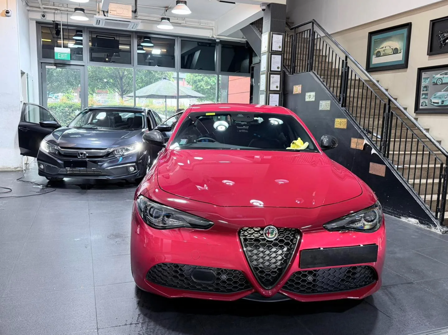 A bright red Alfa Romeo compact saloon viewed from the front in a workshop space.