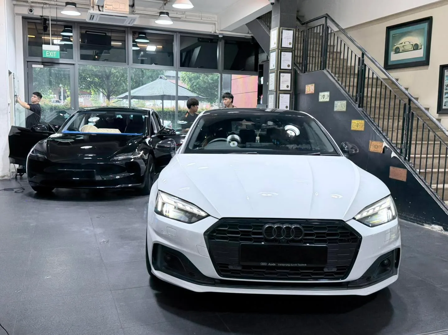 A white Audi A5 saloon parked indoors with a blue sun shade on windscreen.