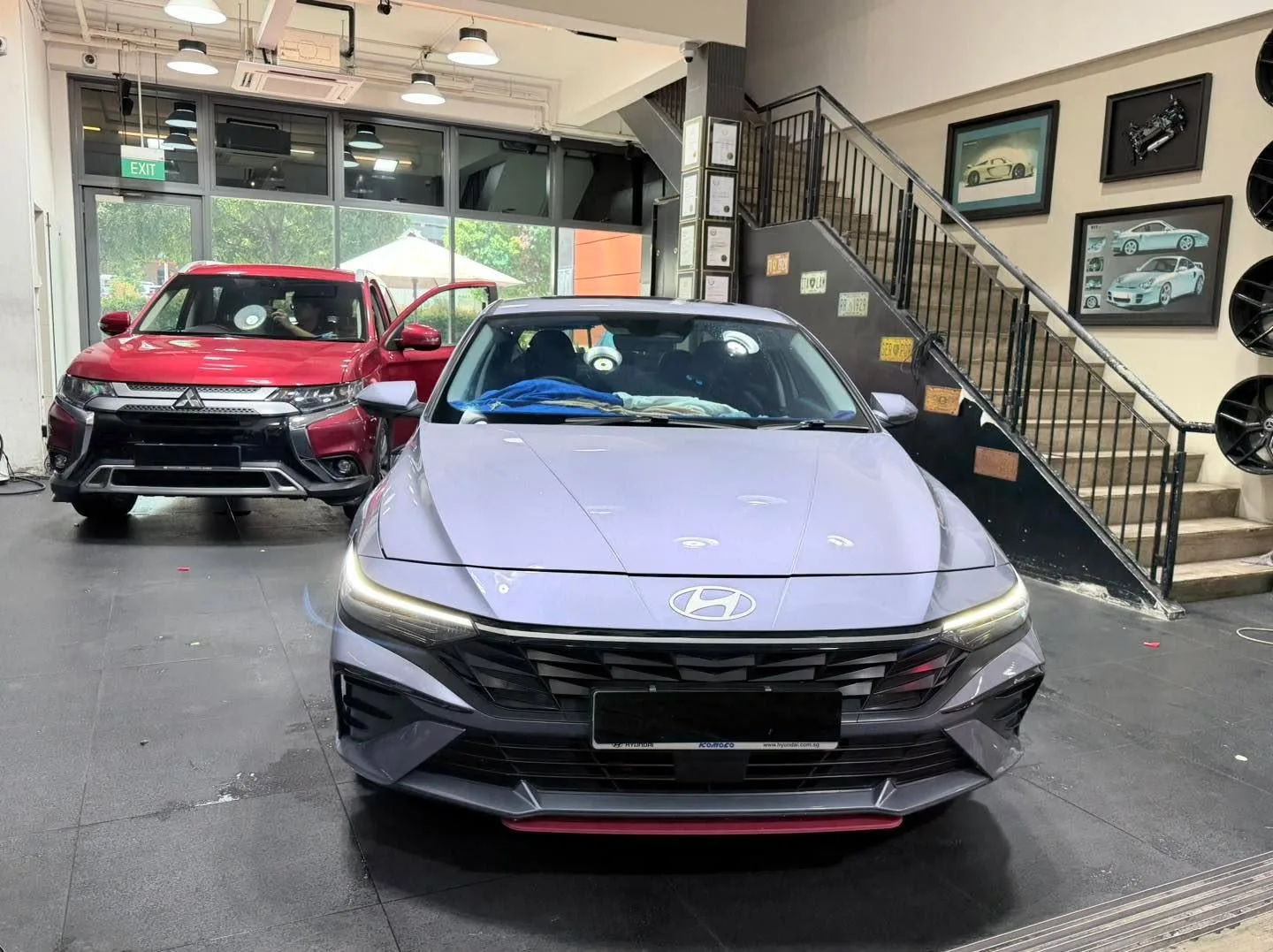 A grey compact sedan, a white compact sedan and a red compact sedan lined up indoors.