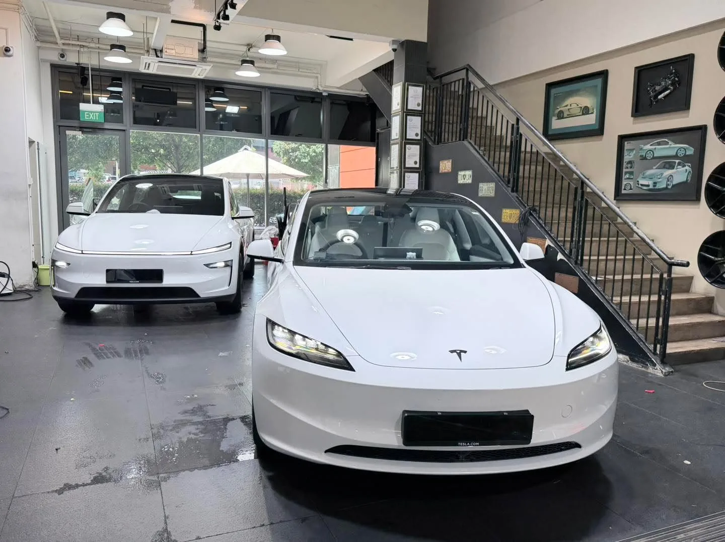 A white electric sedan and a white electric crossover parked indoors.