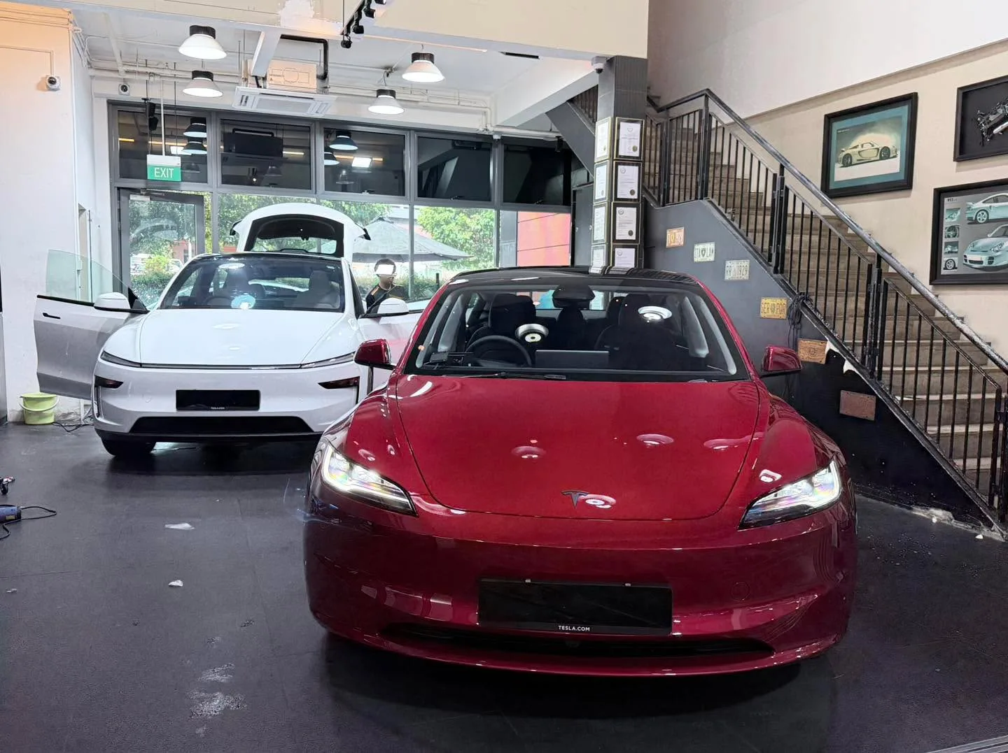 A white compact sedan and a red compact sedan parked indoors.