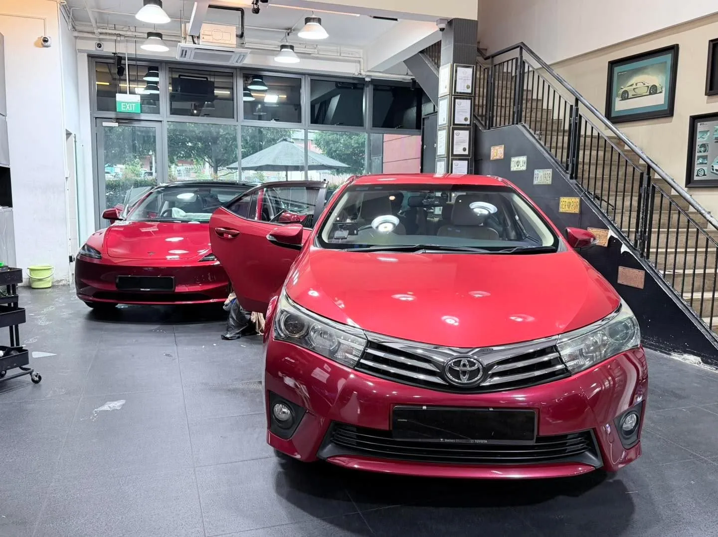 Two red vehicles, a sedan and a coupe, parked indoors.