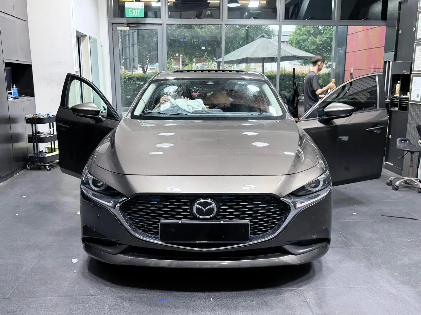 A grey compact sedan with its doors open indoors.