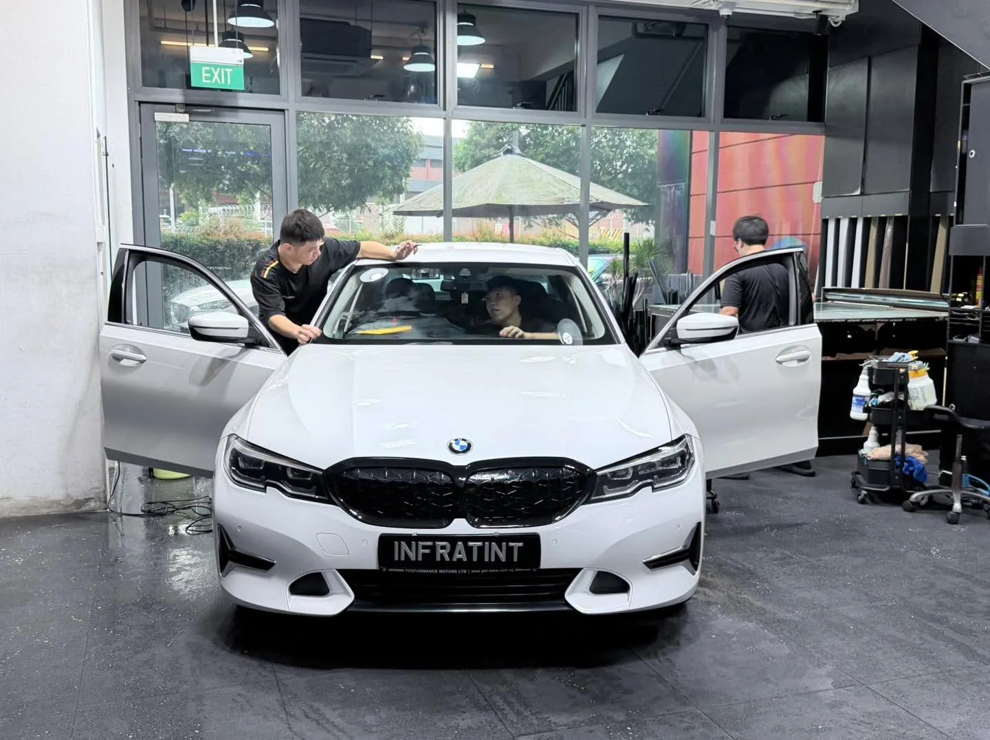 A white BMW sedan with its doors open indoors, being worked on.