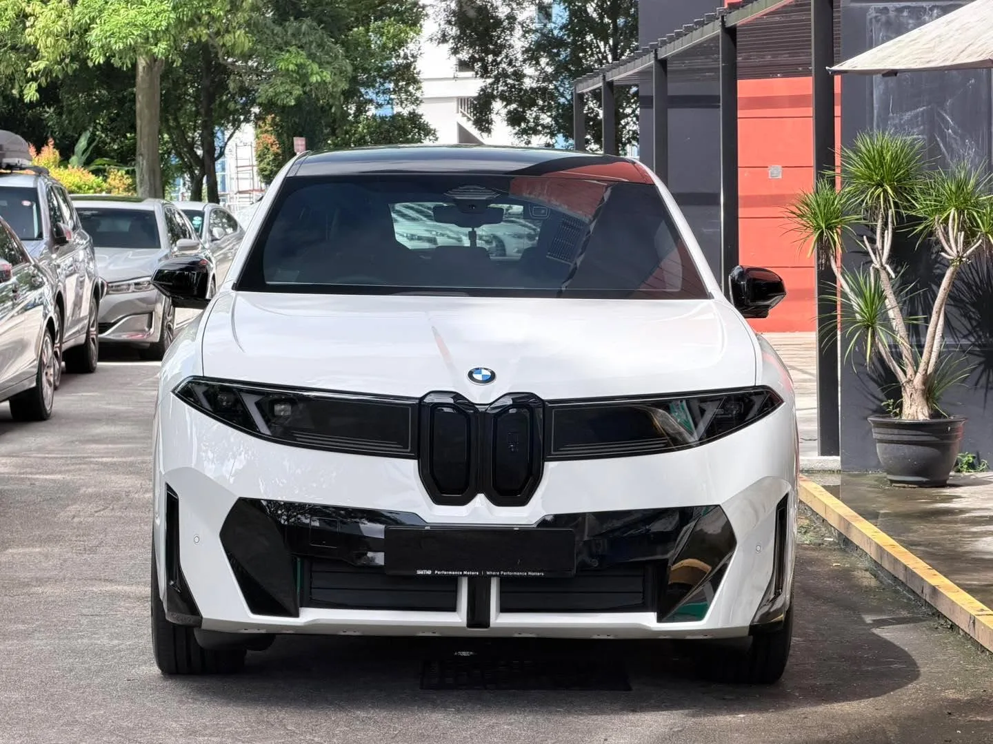 A white BMW iX3 M Sport Pro SUV photographed from the front, parked at Infratint's workshop.
