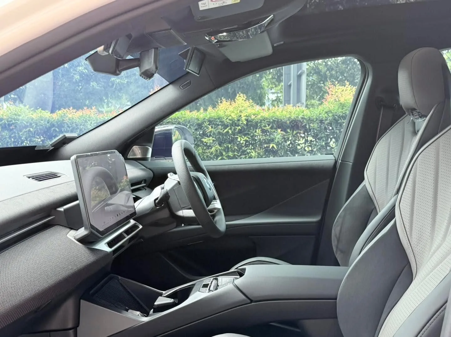 Interior view of the BMW iX3 M Sport Pro showing the steering wheel, dashboard, and tinted windows.
