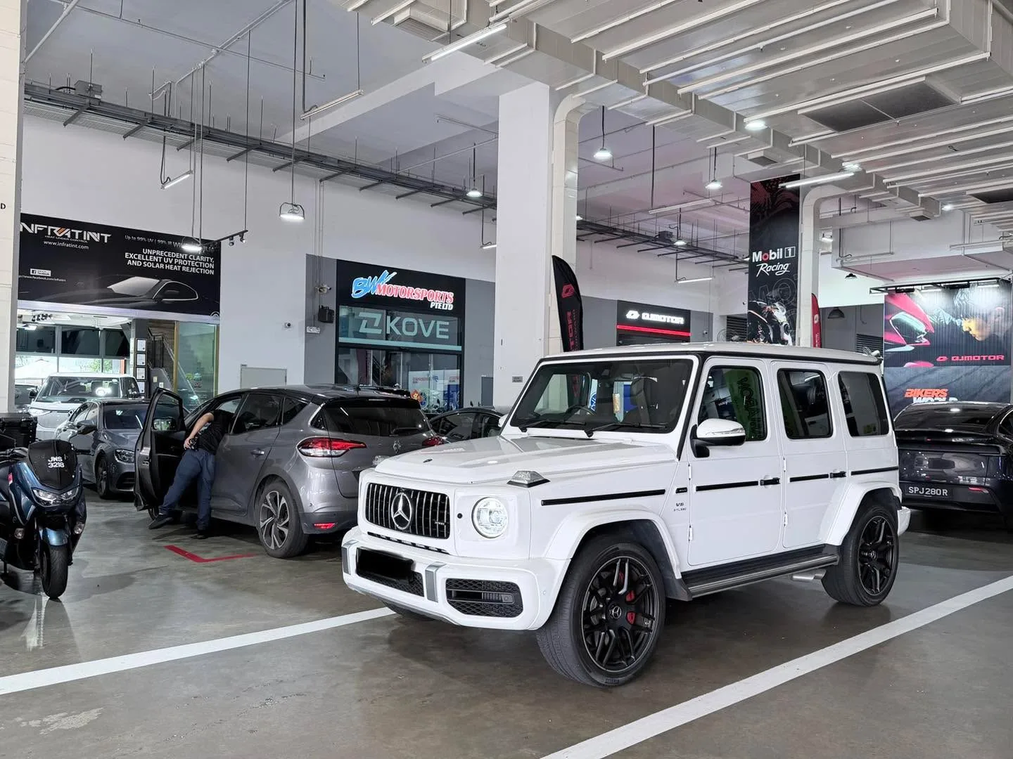 A white Mercedes-Benz G-Class SUV parked in a workshop showroom.