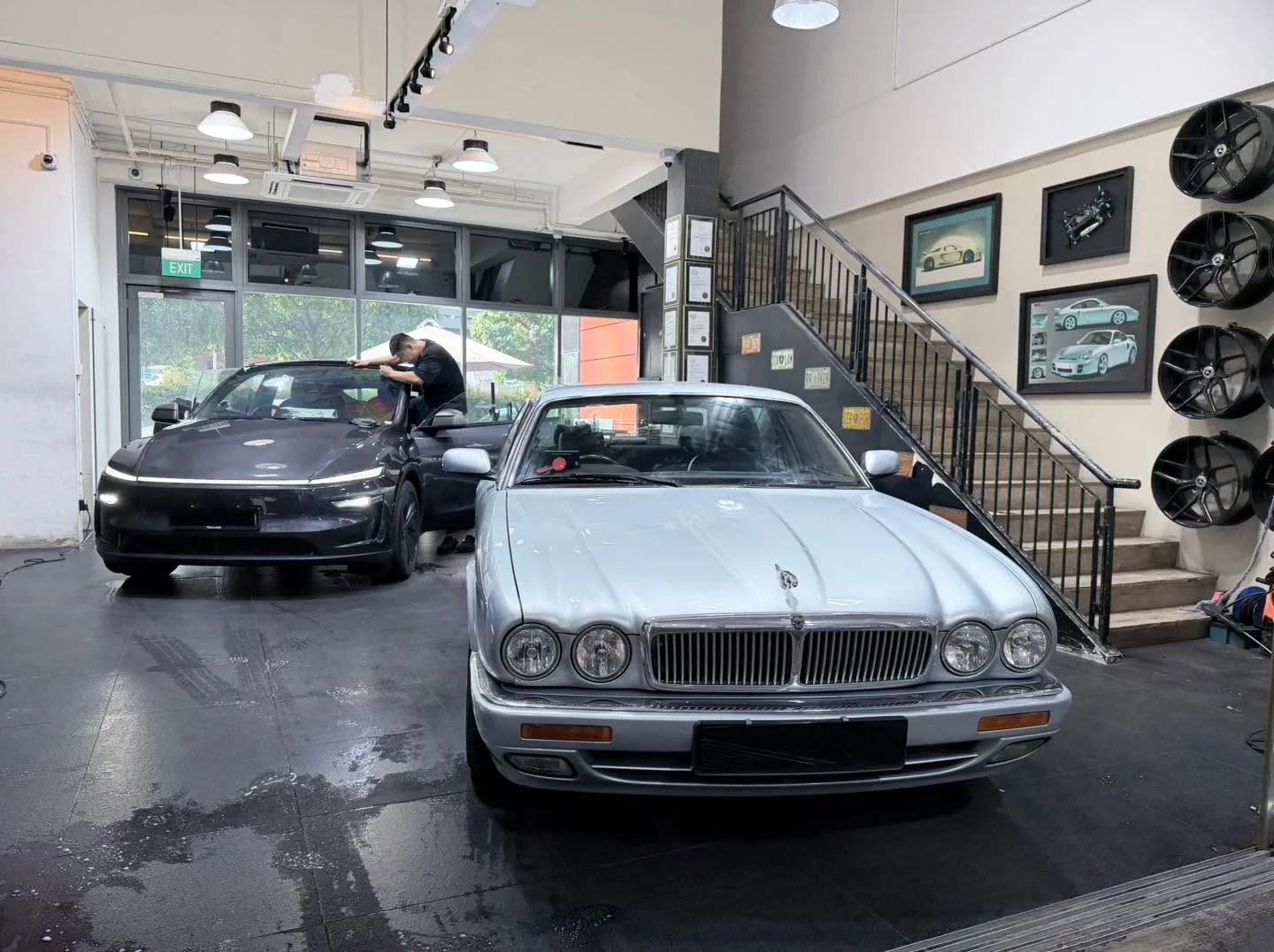 A silver Jaguar XJ saloon parked indoors next to a black Tesla and a dark-coloured car.