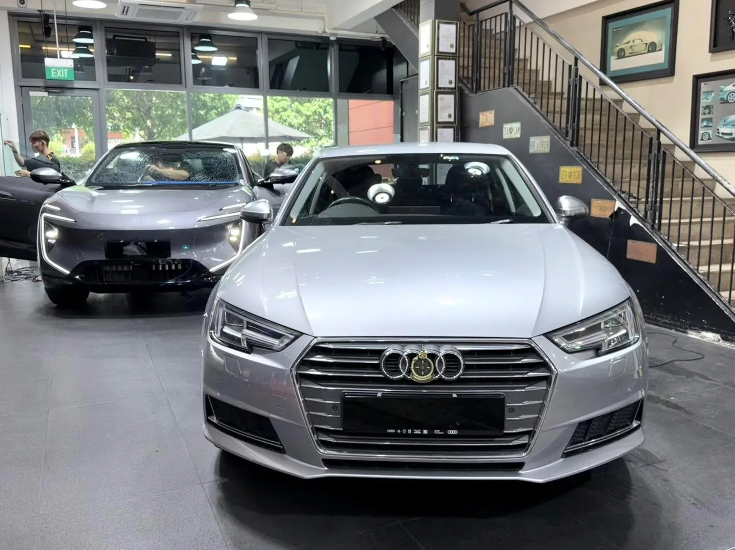 A dark Tesla saloon viewed from the front in the workshop interior.