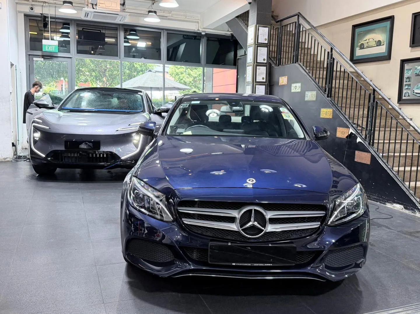A silver Audi A4 saloon parked indoors next to a dark-coloured car.