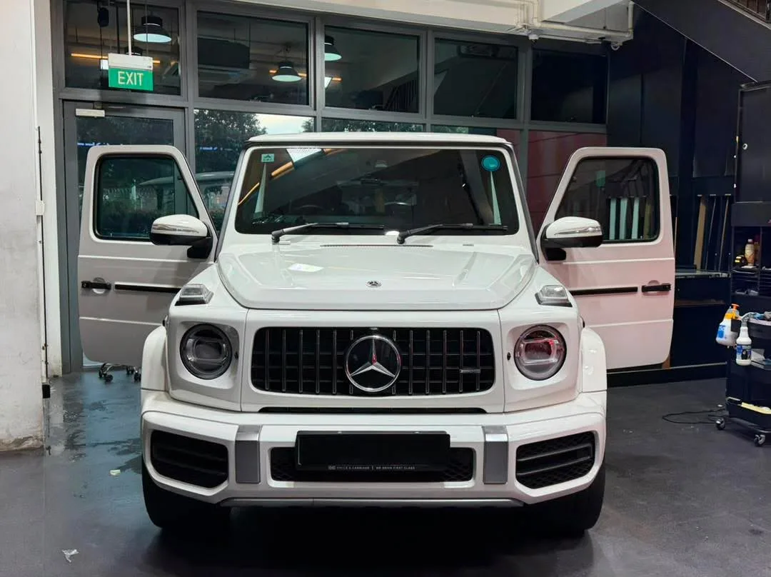 A white Mercedes-Benz G-Class SUV viewed from the front, showing the distinctive grille.