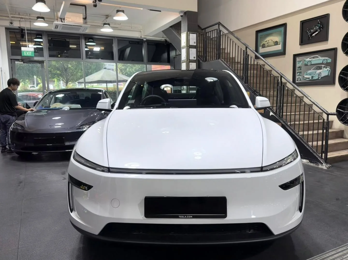 A white Tesla electric saloon photographed from the front in the workshop.
