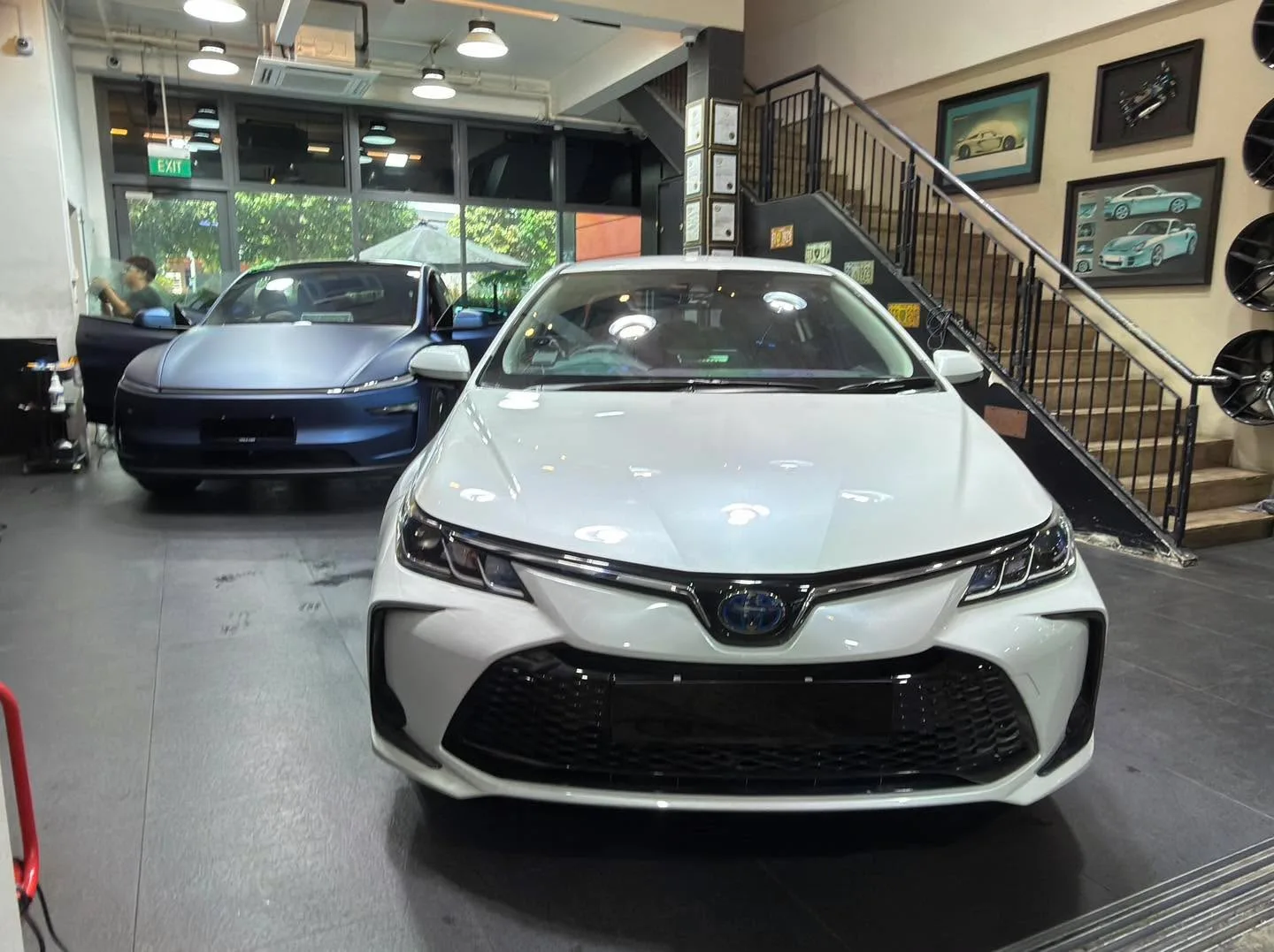 A blue Tesla electric saloon photographed from the front in the workshop.